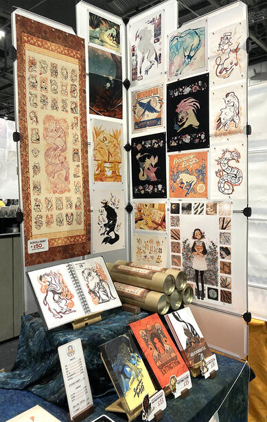 Part of my convention table set-up, featuring printed artwork and books.